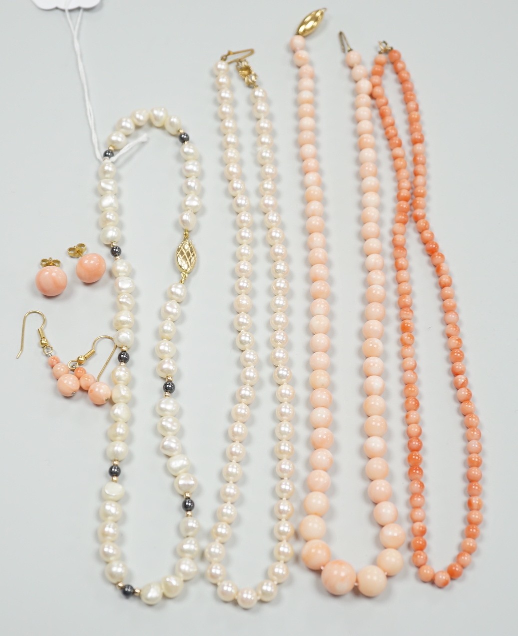 Two modern single strand cultured pearl necklaces, both with 375 clasp, one with hematite beads, longest 42cm, together with two modern coral bead necklaces, one with pair of matching drop earrings.